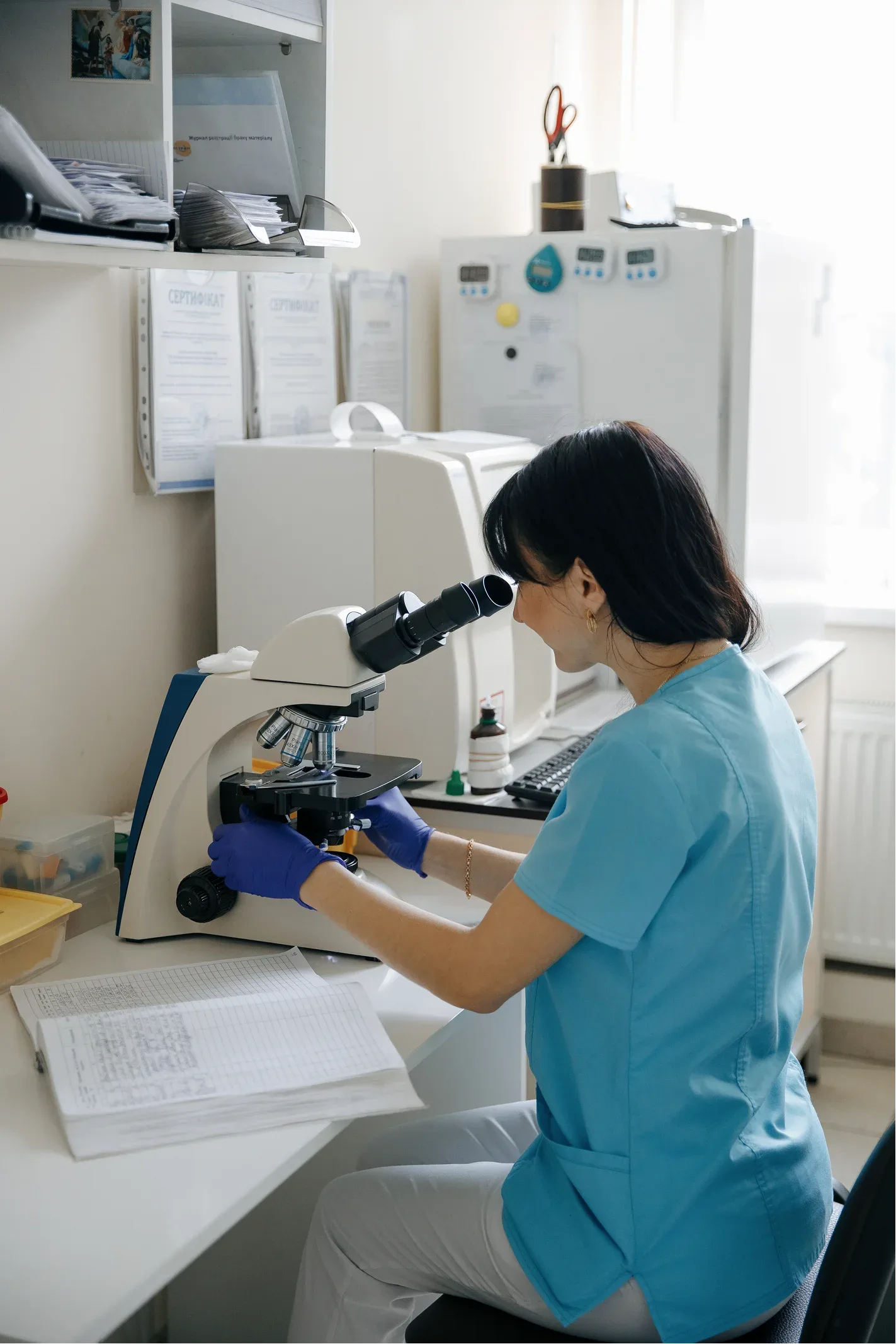 A laboratory technician drawing a sample under a microscope